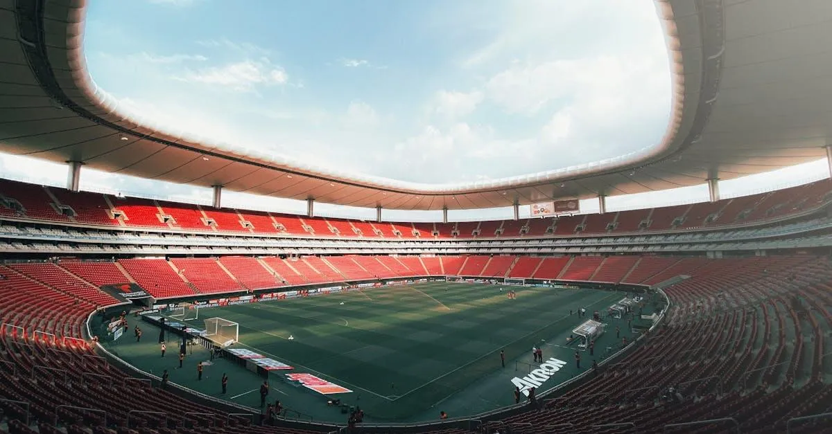 Aerial view of Estadio Akron in Guadalajara, Mexico, showcasing its vast red seating area and green soccer field.