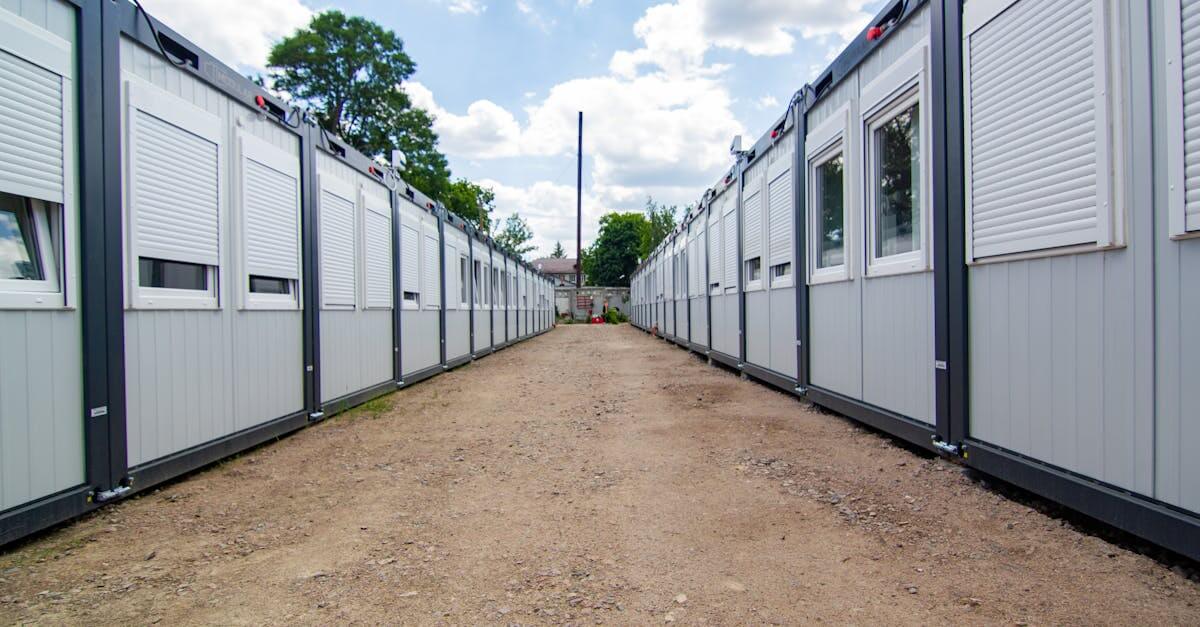 A clear sky view of two rows of temporary office buildings with a dirt pathway in between.
