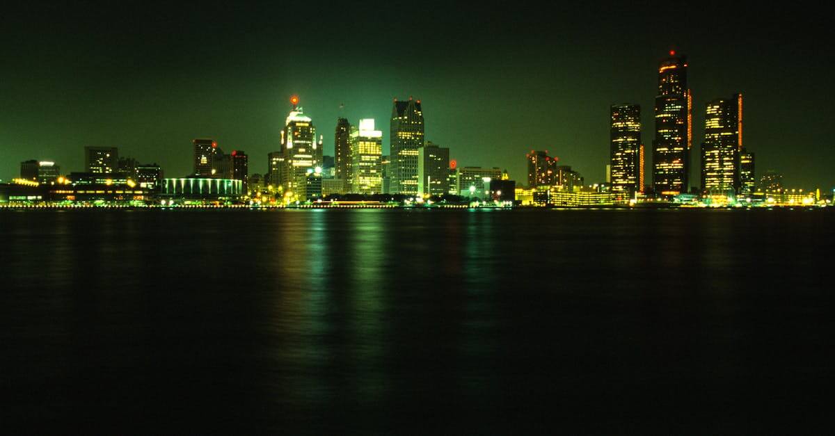 Stunning nighttime view of Detroit's illuminated skyline across a calm river under a dark sky.