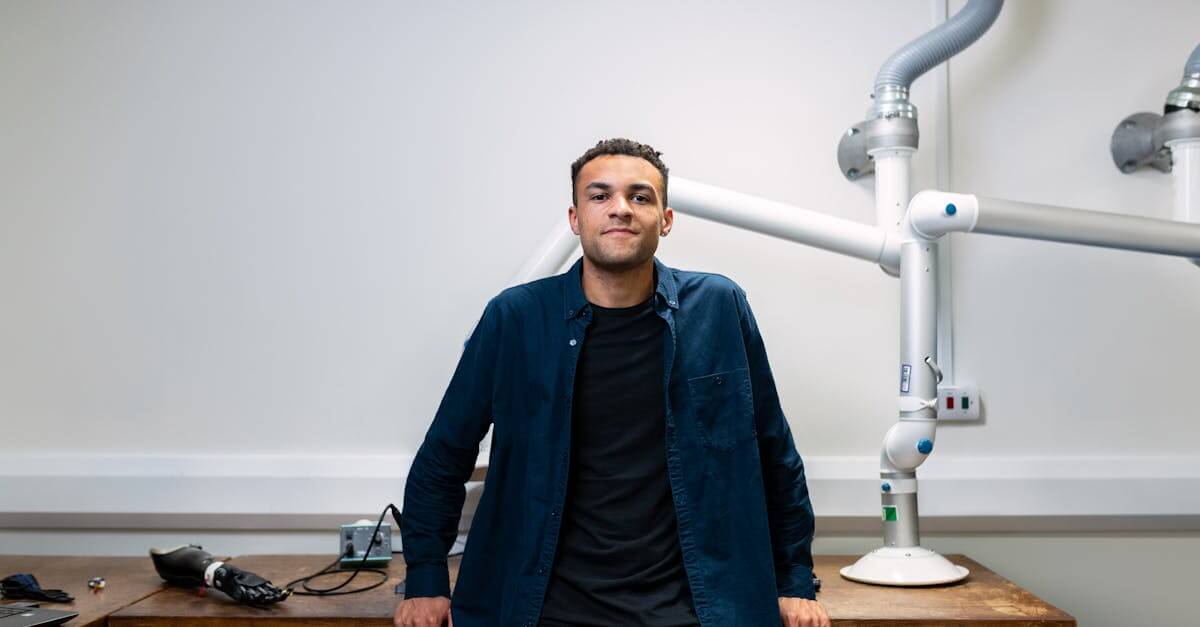 Confident young engineer standing in a laboratory with advanced robotic equipment.