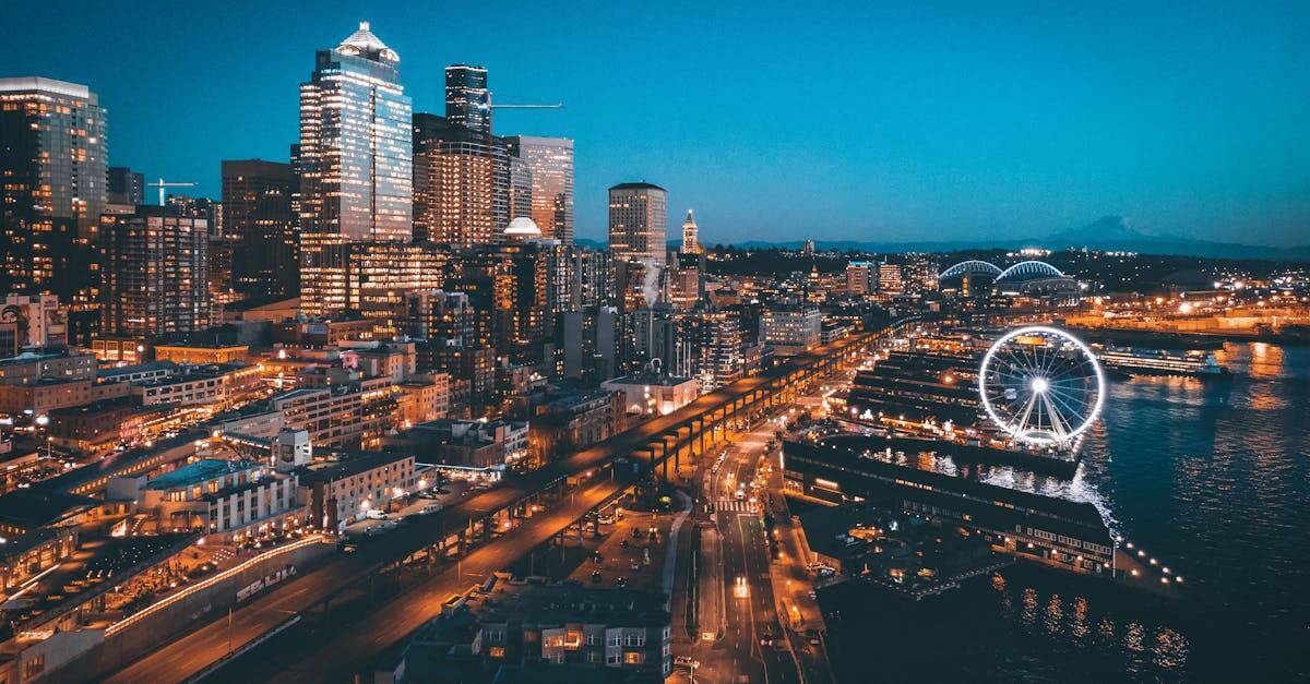 A stunning aerial view of Seattle's skyline at night featuring the illuminated Ferris wheel and waterfront.