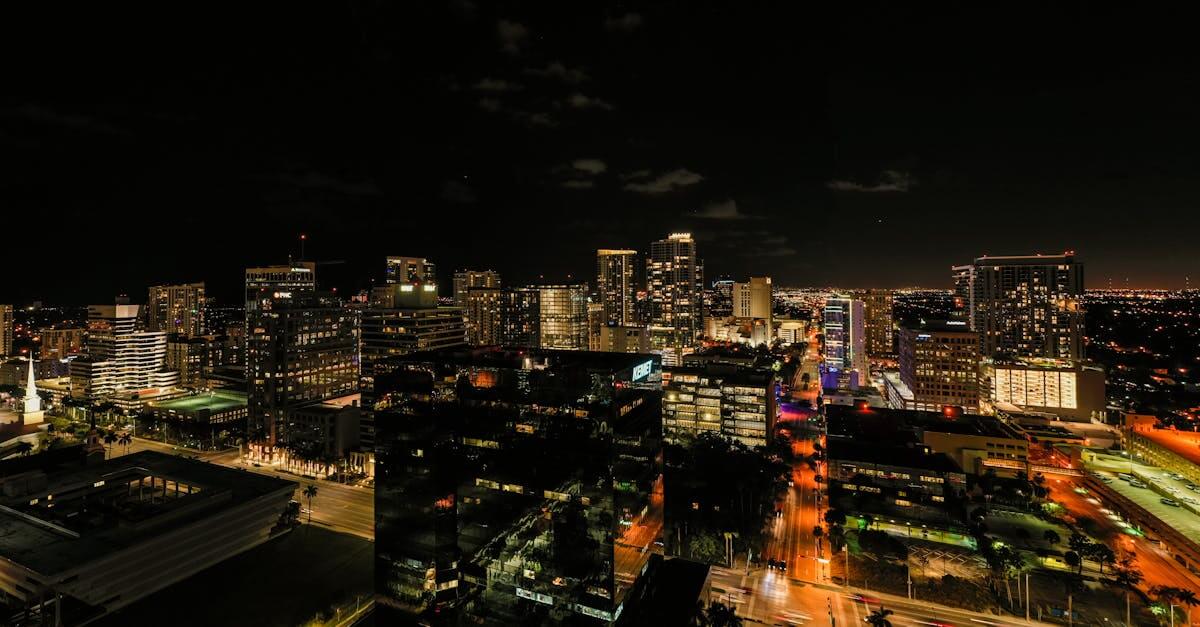 Drone view of asphalt roads and skyscrapers with glowing light and neon illumination in Fort Lauderdale at night