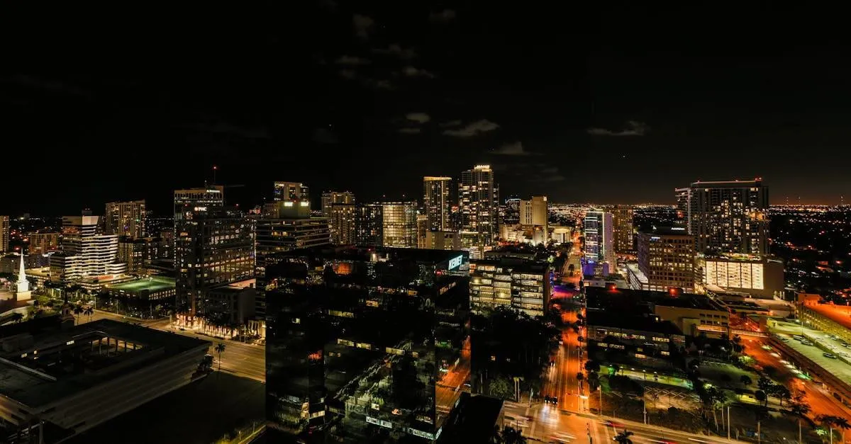 Drone view of asphalt roads and skyscrapers with glowing light and neon illumination in Fort Lauderdale at night