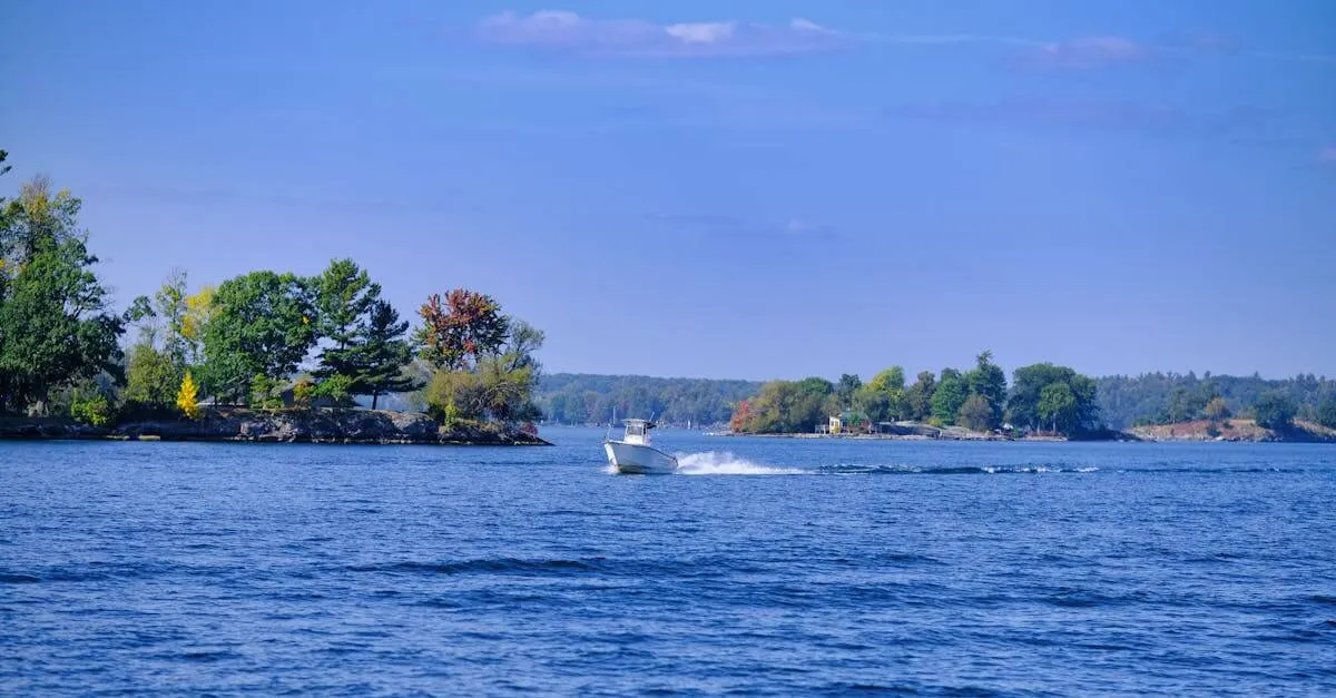A serene lake with a boat cruising past vibrant autumn foliage under a clear blue sky.