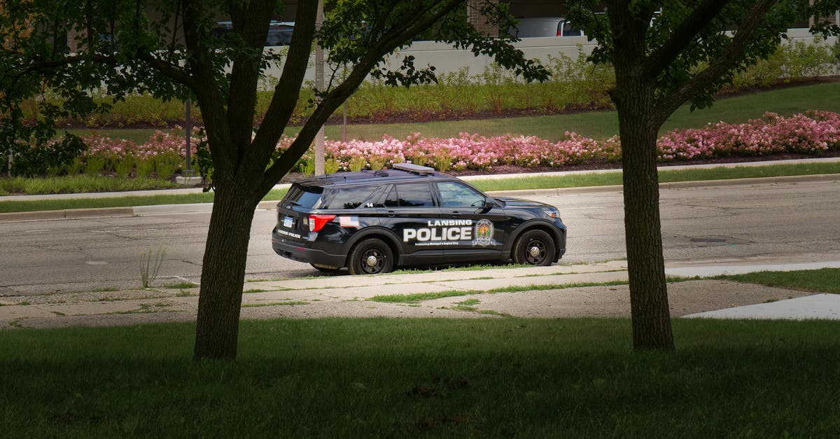 Lansing police vehicle parked in a lush city park with flowers and trees.