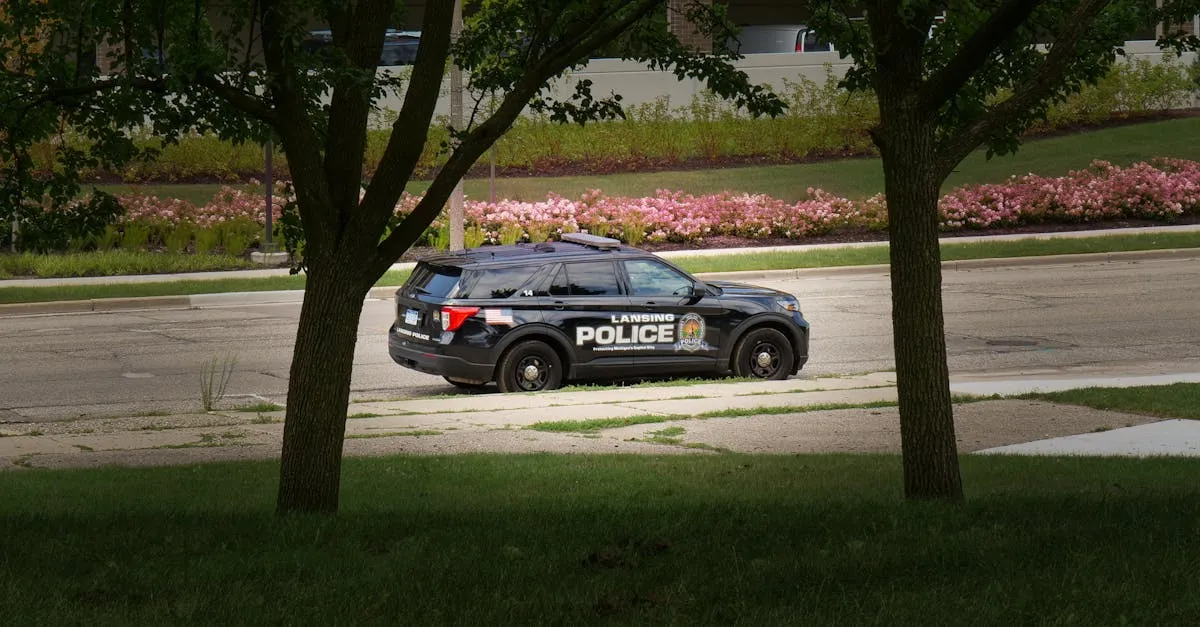 Lansing police vehicle parked in a lush city park with flowers and trees.