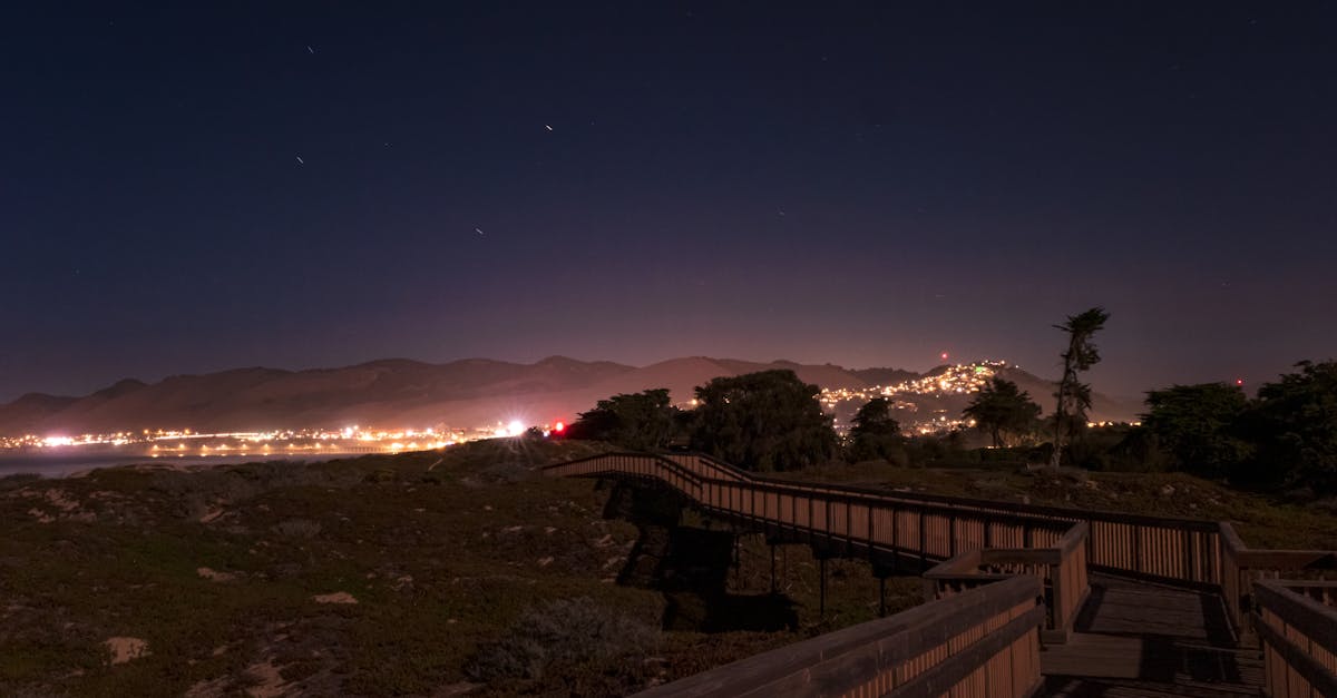 Nighttime view of Pismo Beach boardwalk with city lights and clear sky.
