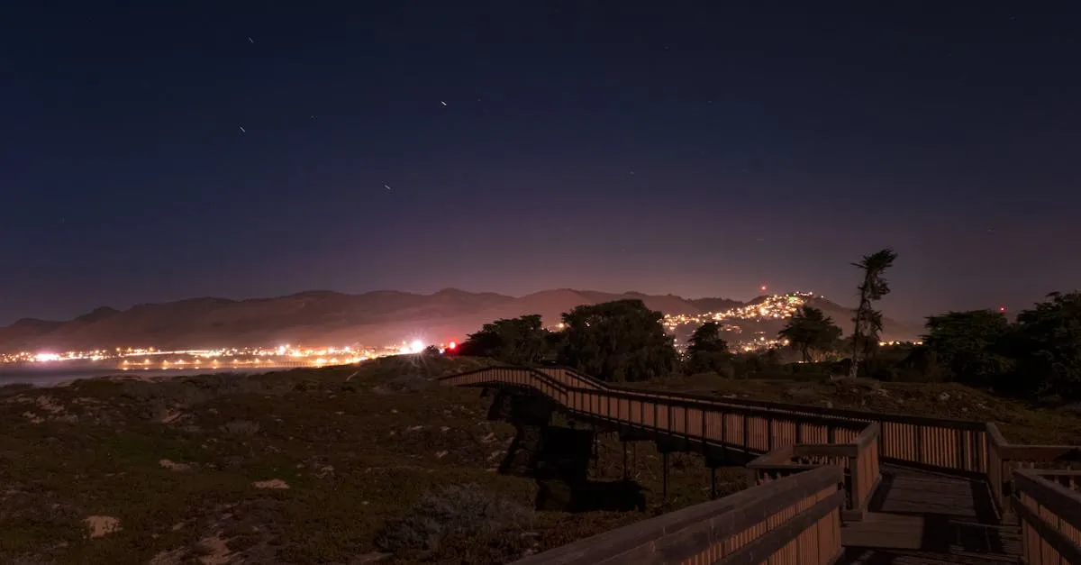 Nighttime view of Pismo Beach boardwalk with city lights and clear sky.