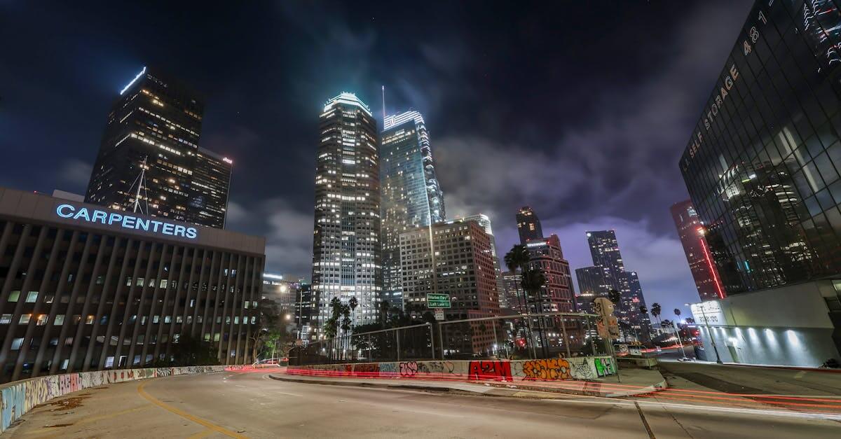 Vibrant night view of downtown Los Angeles with illuminated skyscrapers and light trails.