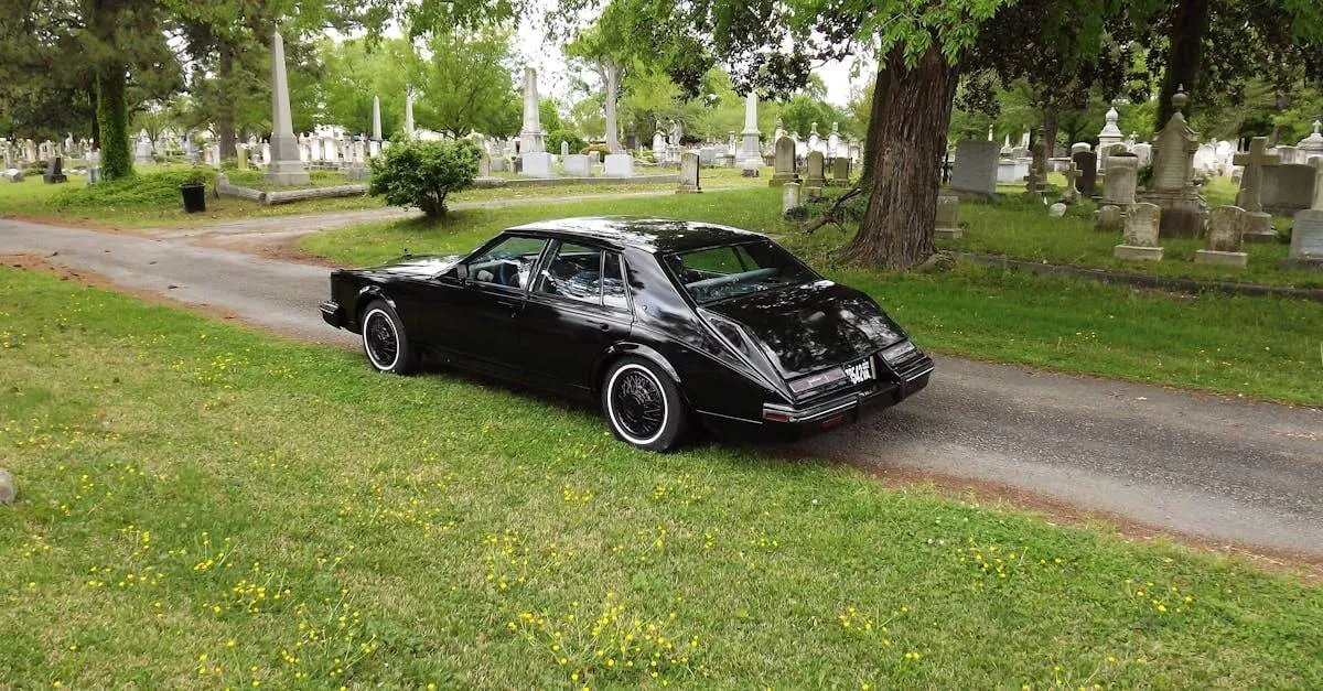 A classic black car parked on a serene pathway in an old cemetery in Norfolk, VA.