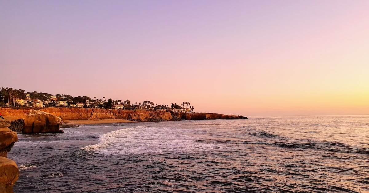 A tranquil sunset view of the San Diego coastline with calm waves and vibrant skies.