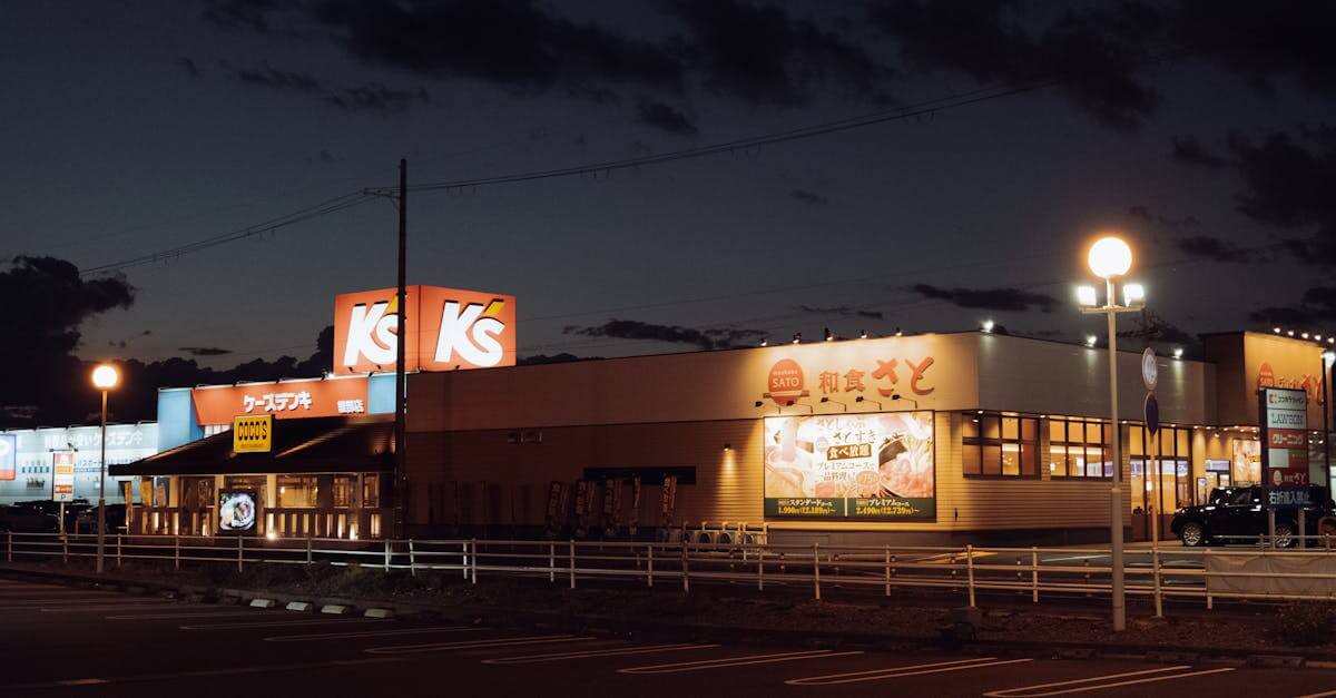 A vibrant night scene of commercial buildings in Kyoto, Japan with illuminated store signs.