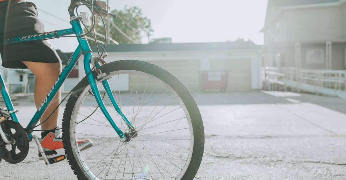 Teen biking along an urban street with sunlight, focusing on teal bicycle and vibrant atmosphere.
