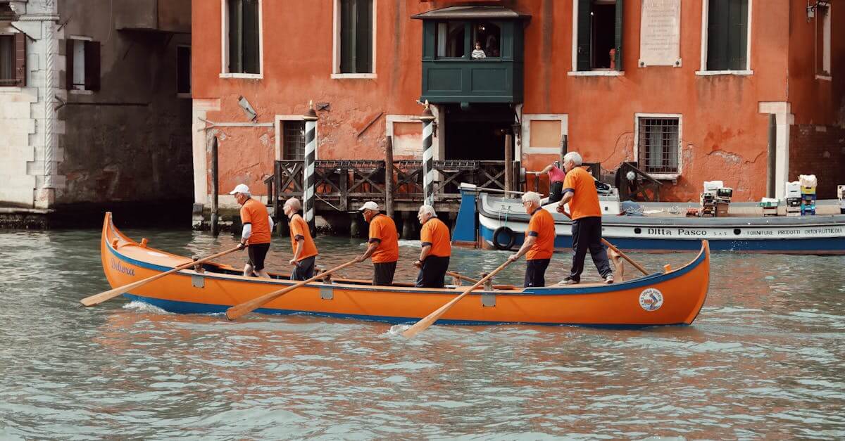 Group of senior men rowing an orange boat along a canal in picturesque Venice, Italy.