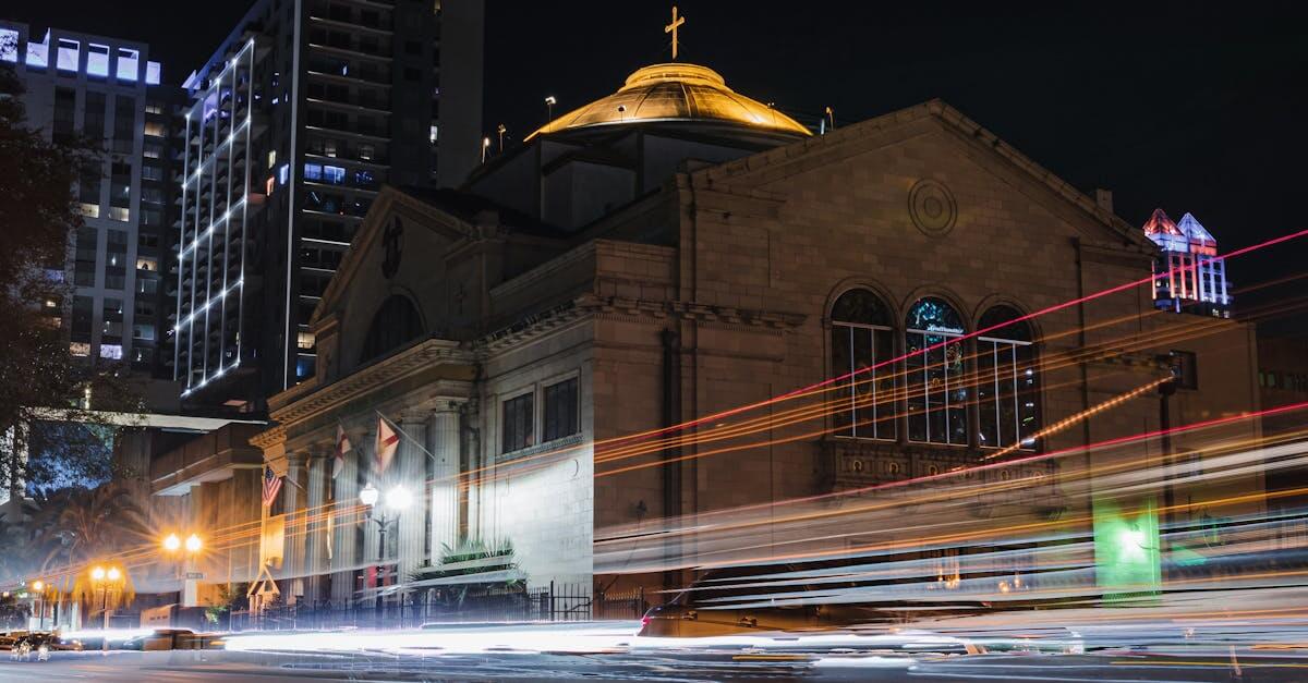 A stunning night view of a church in downtown Orlando with vibrant light trails from passing cars, highlighting urban life.