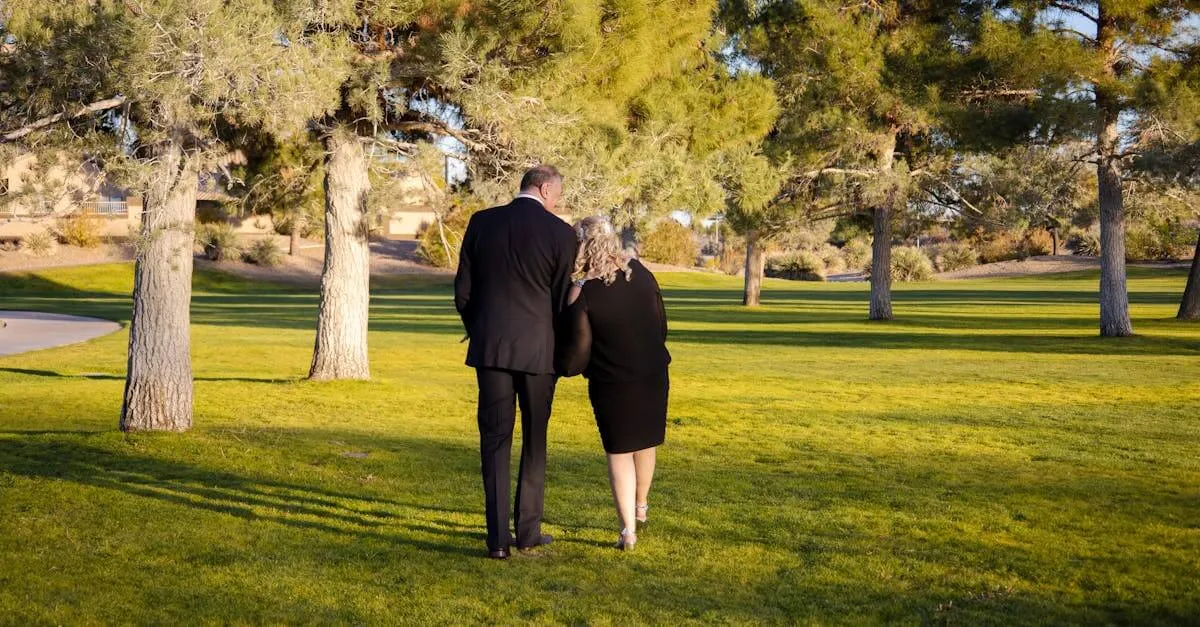 A couple walking arm-in-arm in a sunny park, surrounded by trees and grass.