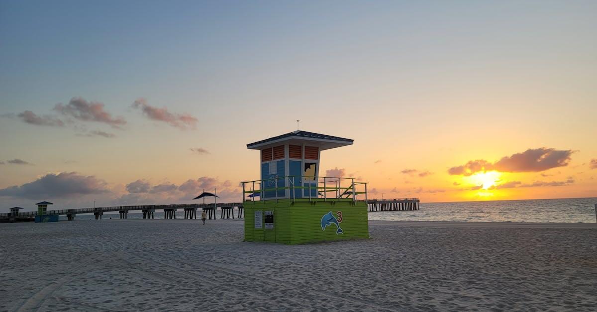 Colorful lifeguard tower at Pompano Beach during a serene sunrise over the ocean.