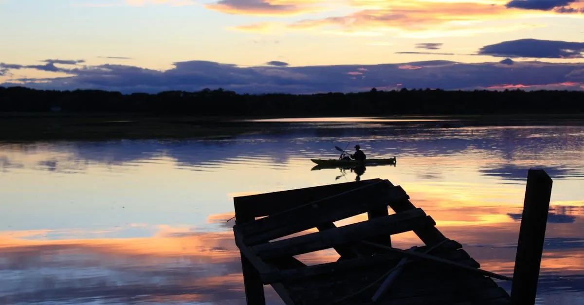 Serene lake view with silhouetted canoeist at sunset in Scarborough, Maine.
