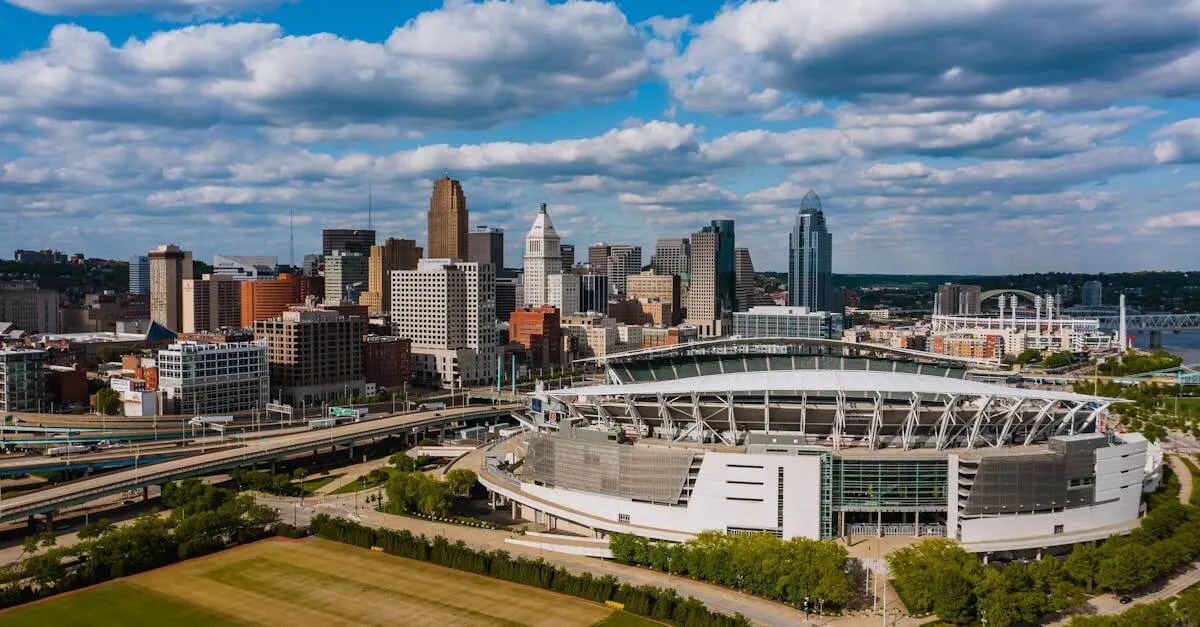 Exterior of modern Soldier Field in America surrounded by green trees and high multi storey office building next to junction and lawn